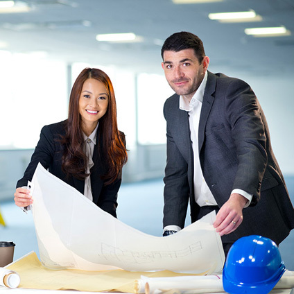 A man and a woman looking over at some building plans