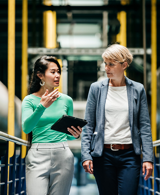 Two women busily talking on a factory floor