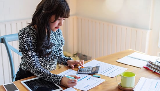 woman sitting on an office desk, doing accounting sheets