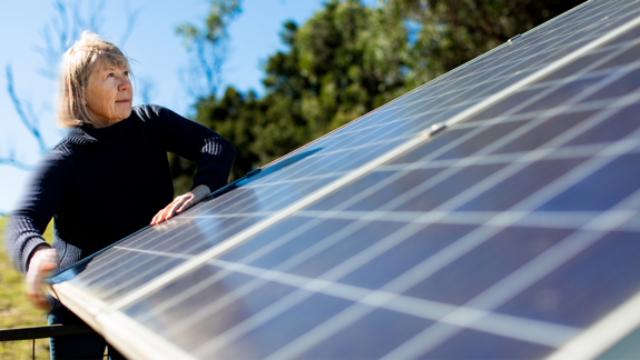 woman looking at a solar panel in a field