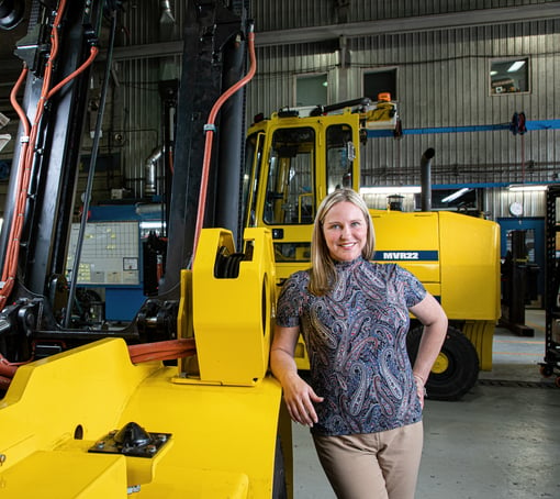 eloise harvey leaning against heavy machinery in a factory