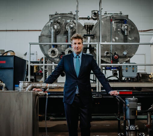 Martin Popiel standing in his factory in front of a large machine