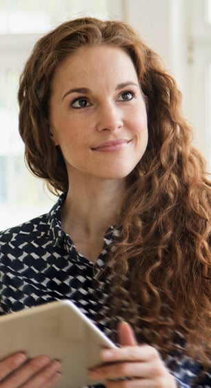 Red curly hair woman smiling and holding a tablet