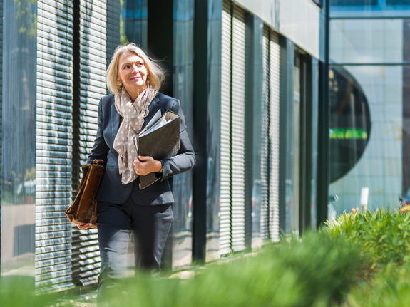 woman walking next to a building with plants 