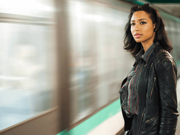 woman next to a subway, watching as it passes by