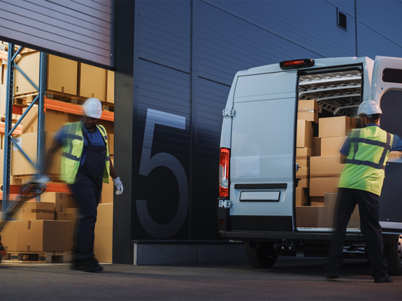 men moving a fork lift full of boxes to load in a van 