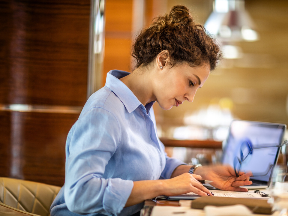 Woman reading financial indicators with glasses in her left hand