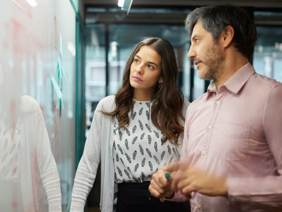 Two colleagues analyzing data on a board