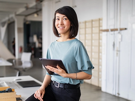 femme d'affaires debout dans son bureau avec une tablette dans les mains
