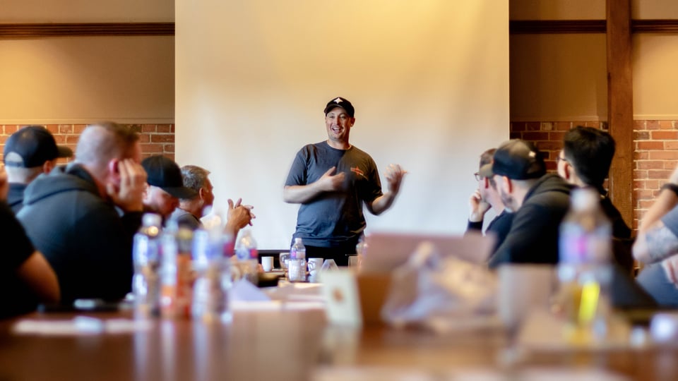 Aaron Jones, CEO of Kraun Electric, speaks to a group of people gathered around a table.