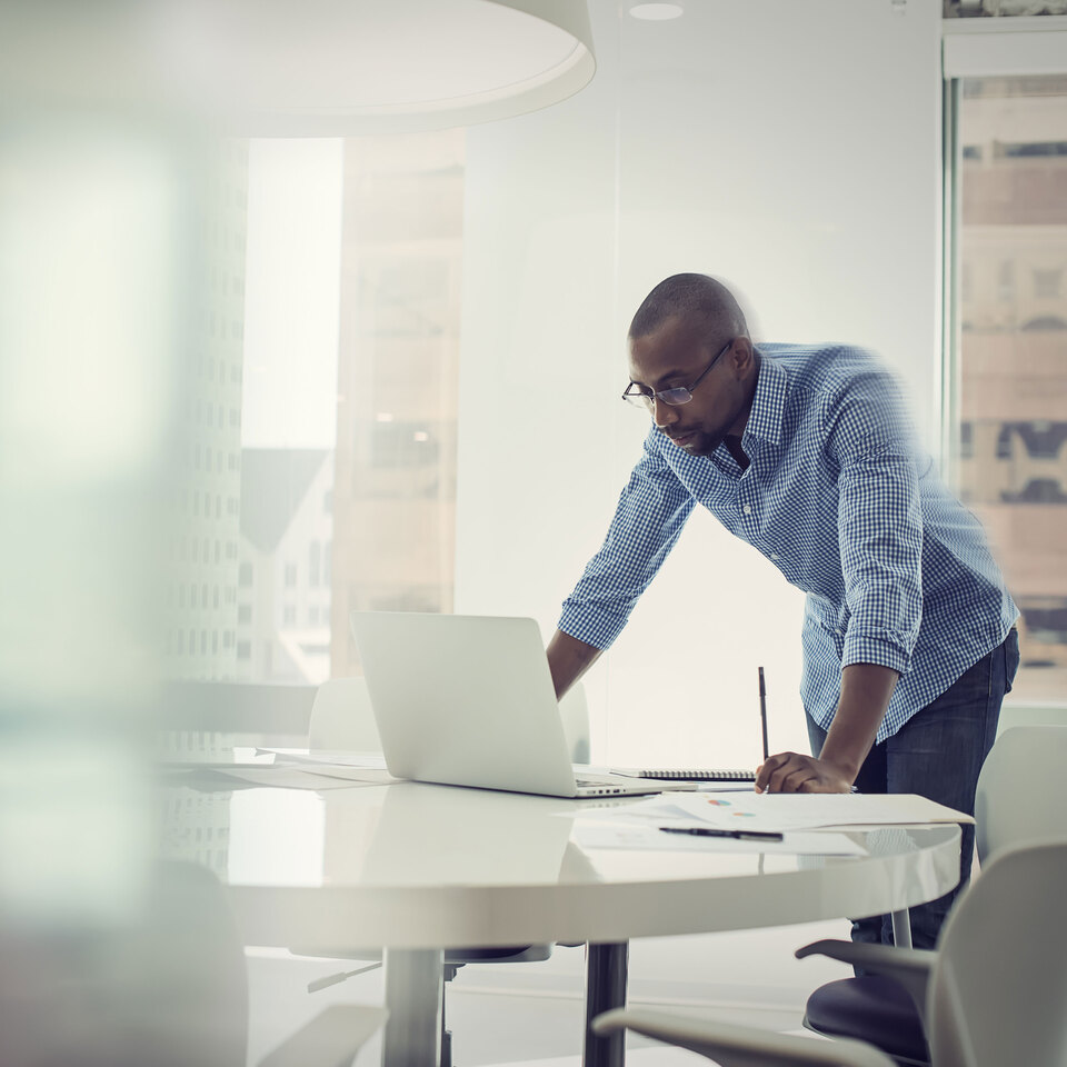 black businessman working in a brightly-lit office on a computer