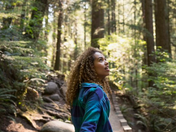 jeune femme en randonnée dans les bois, levant les yeux avec admiration
