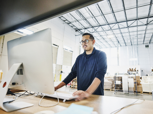employé d'entrepôt masculin vérifiant les commandes au poste de travail informatique
